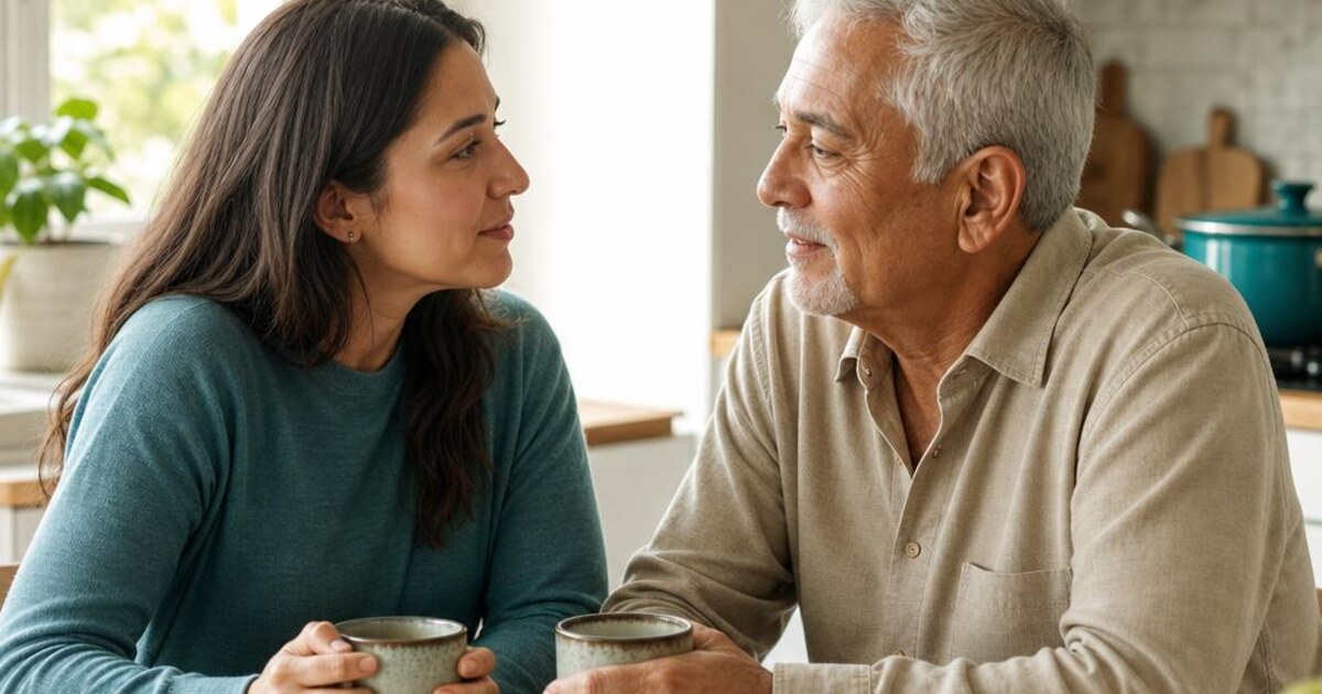 An adult daughter and her older father talking together at a kitchen table